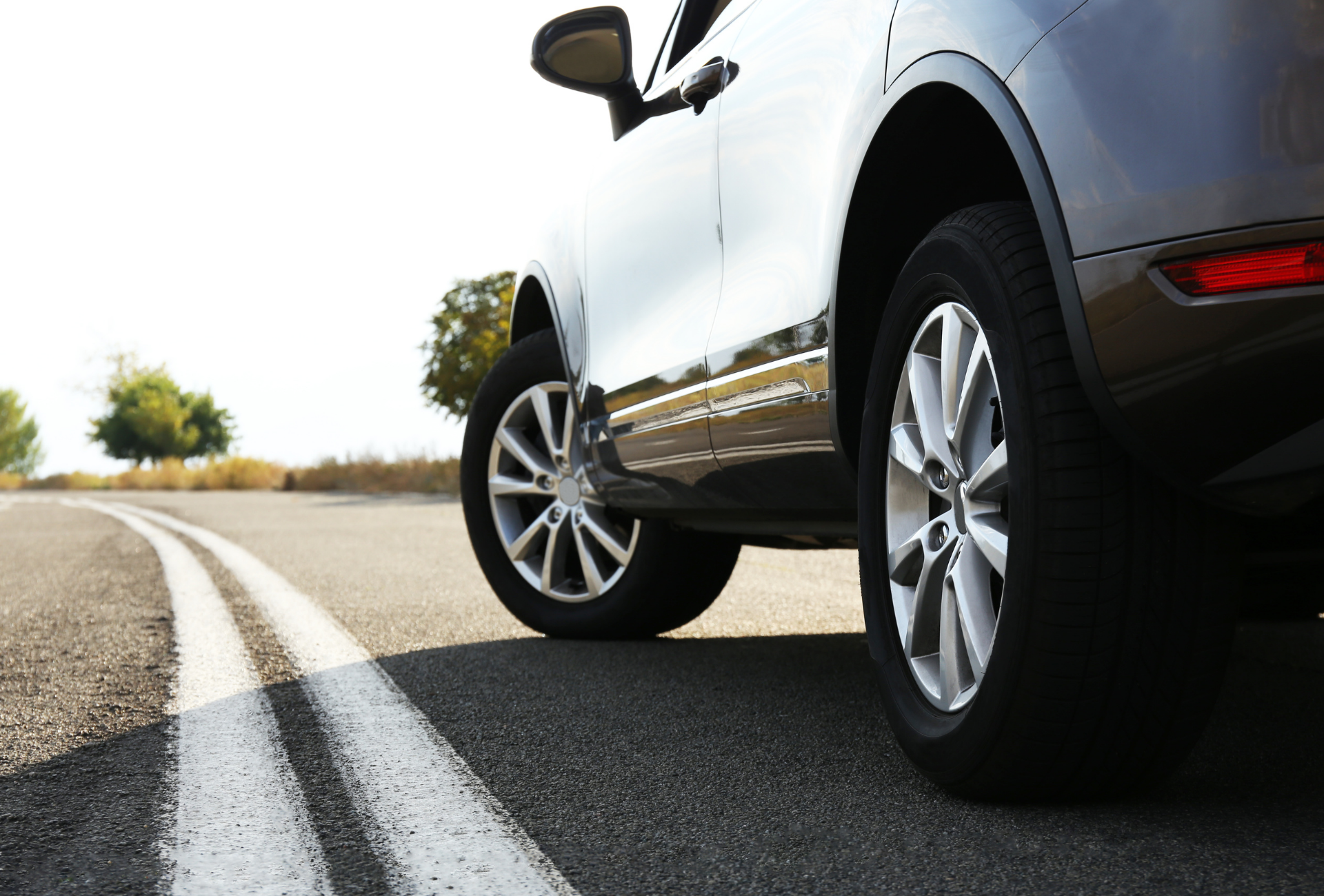 White cargo van at a crosswalk in a city, with a pedestrian in the background.