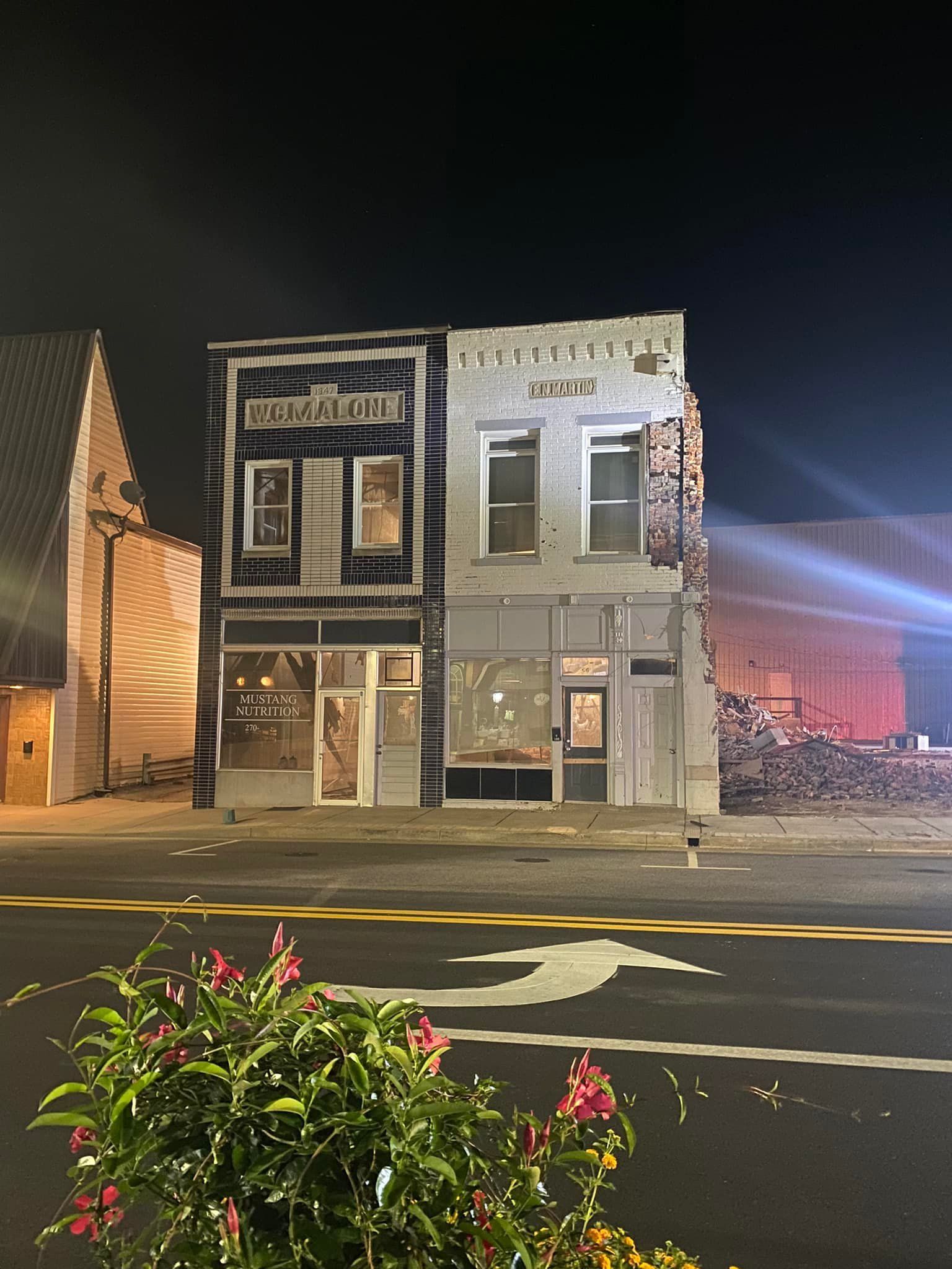 Two adjacent two-story commercial buildings at night, featuring a dark facade on the left.
