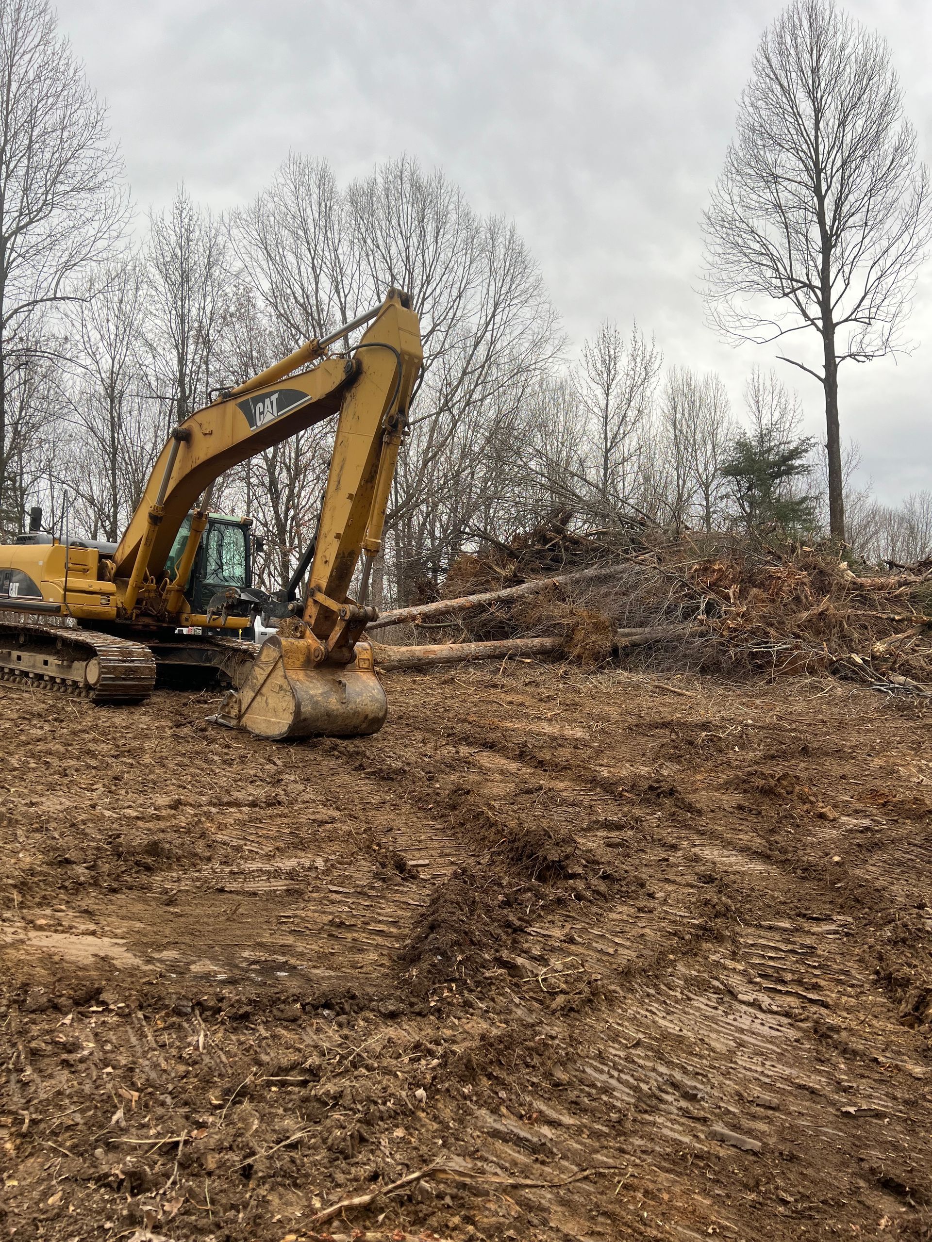 A yellow Caterpillar wheel tractor-scraper working on a dirt field under a cloudy sky.
