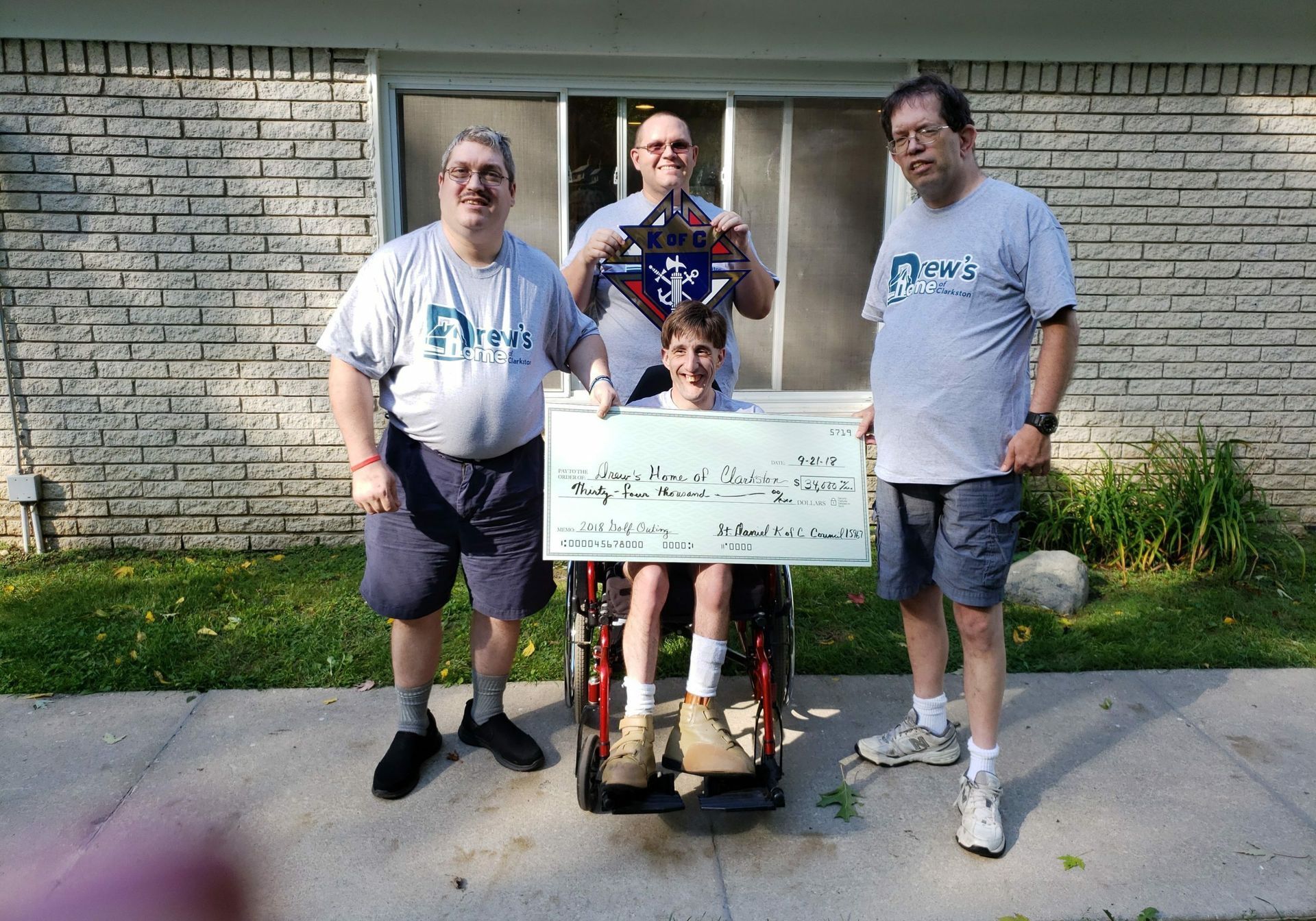 A boy in a wheelchair is holding a large check