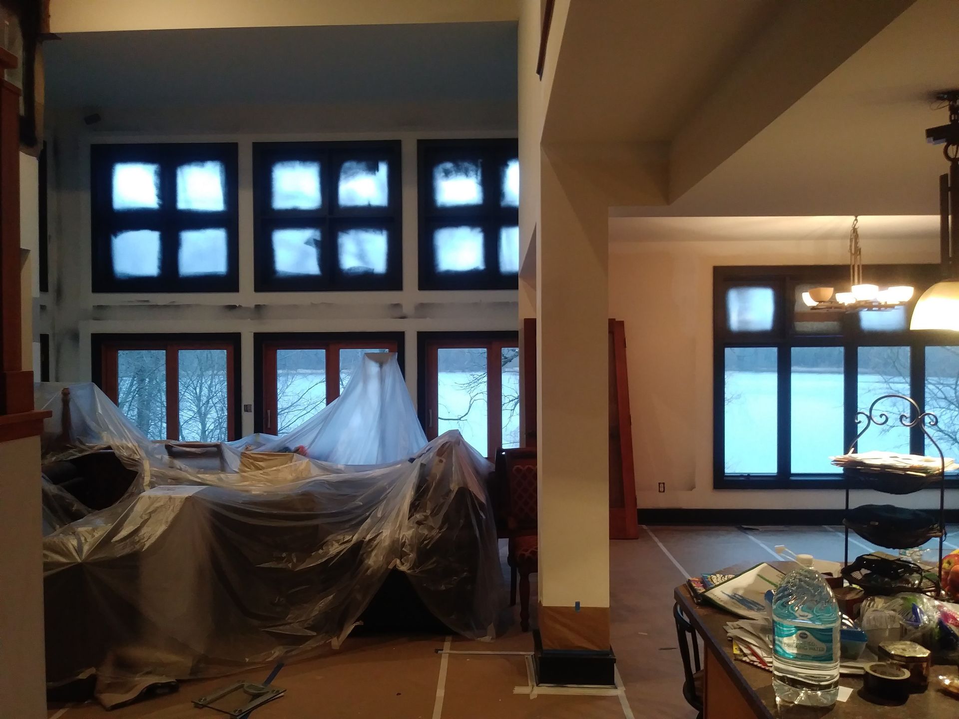 A room with a lot of windows and a table with a bottle of water on it