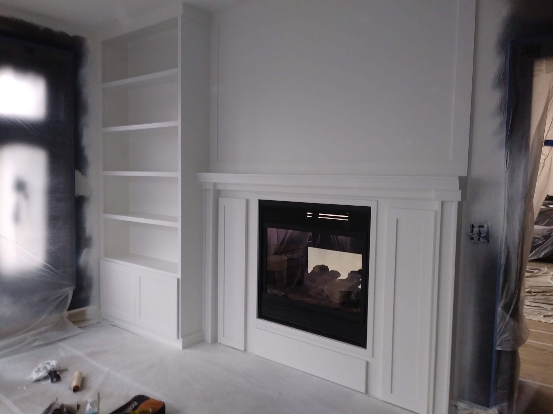 A living room with a fireplace and shelves in it.