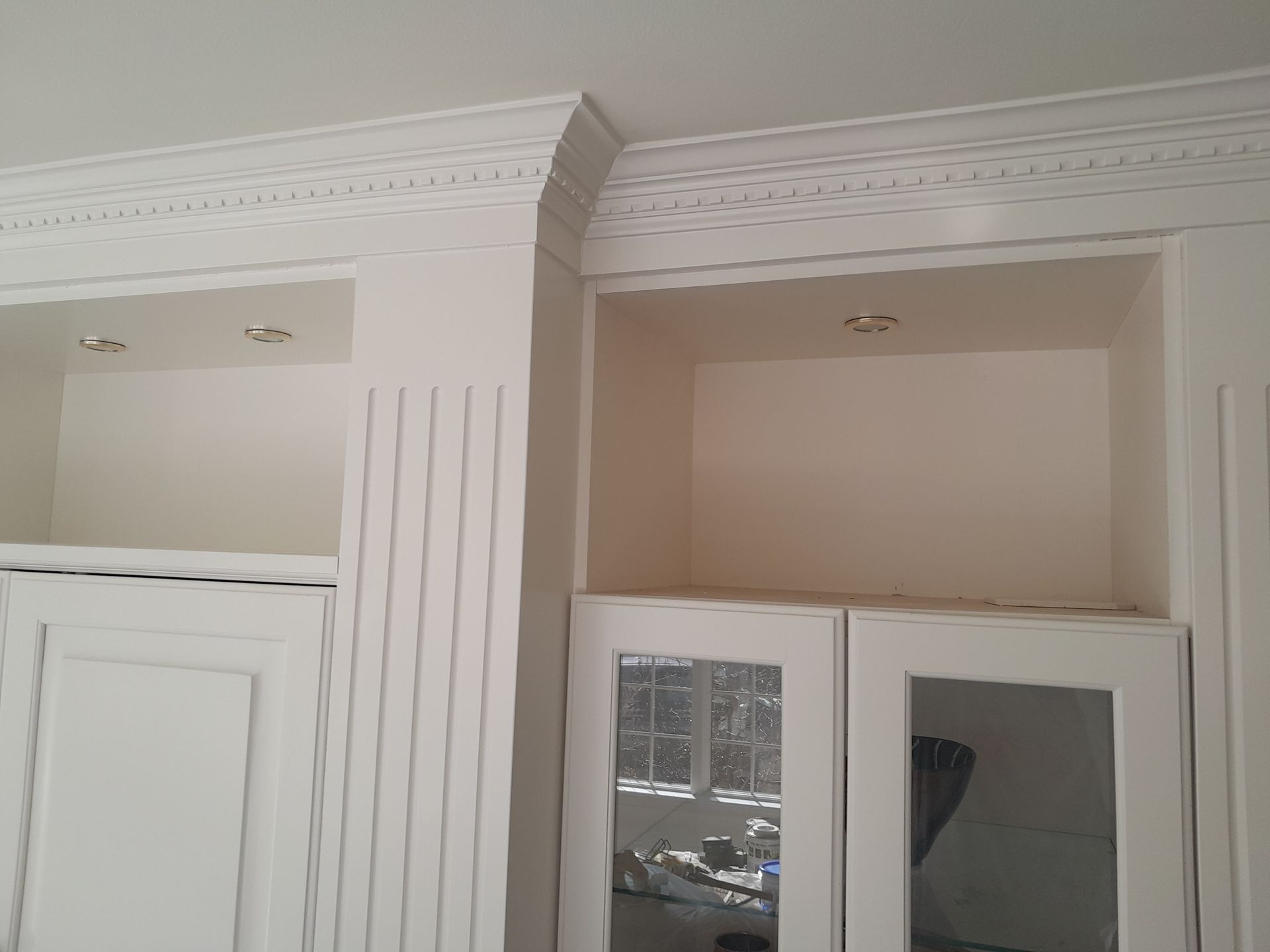 A room with white cabinets and a mirrored door