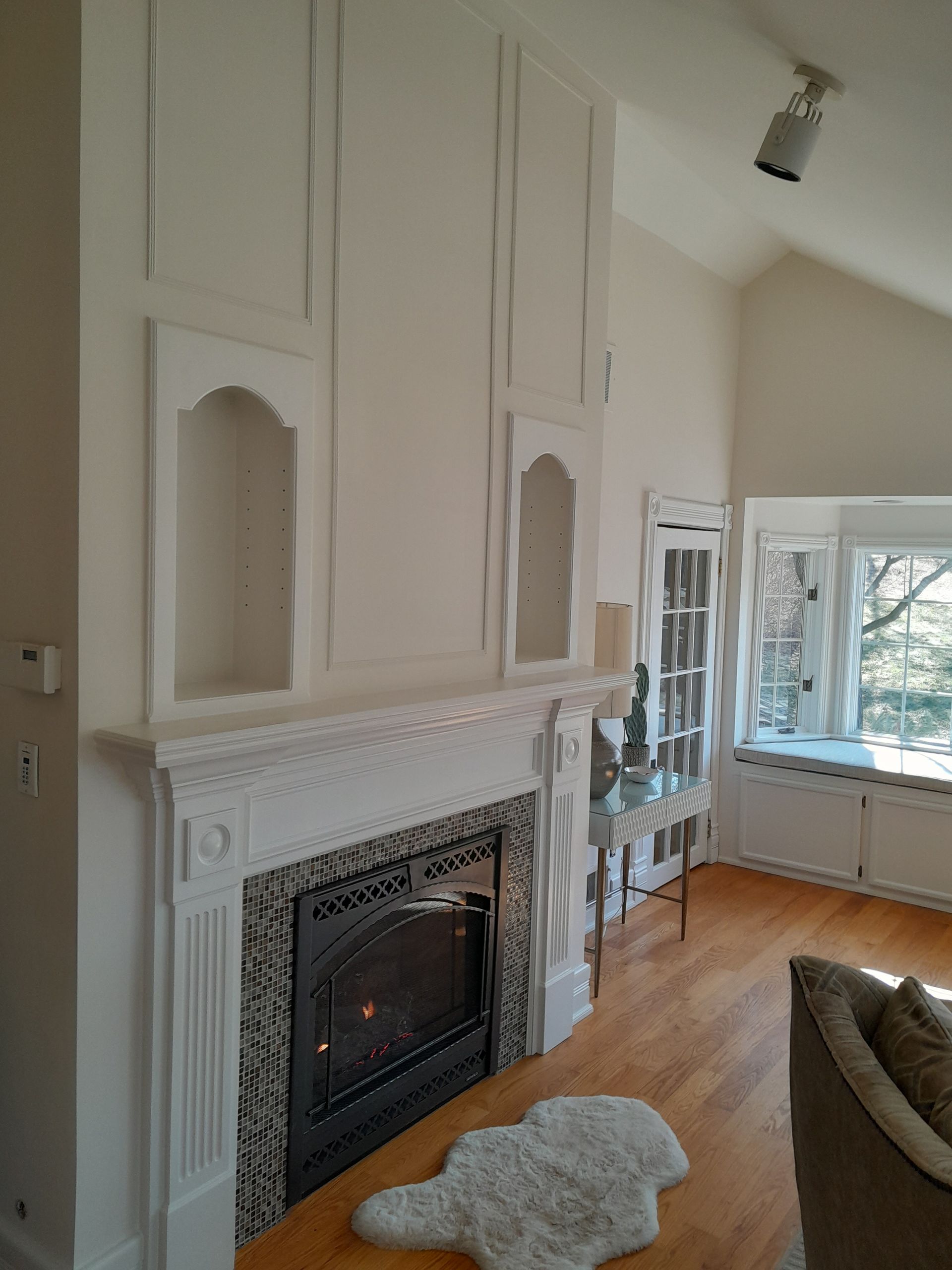 A living room with a fireplace and a rug on the floor.