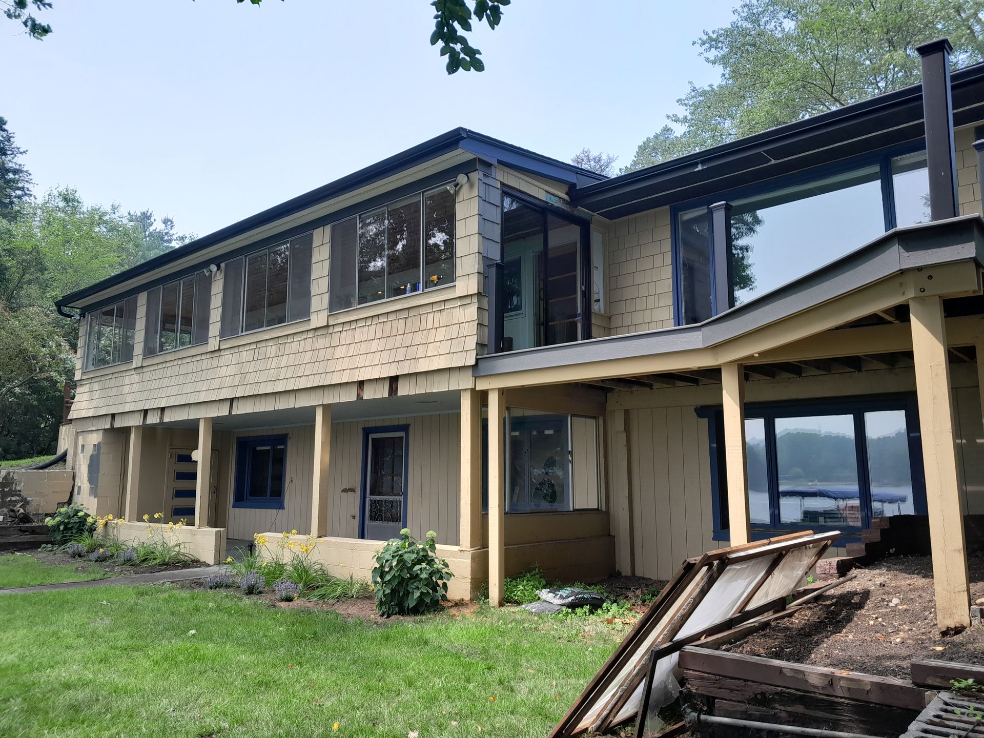 A large house with a lot of windows is sitting on top of a lush green field.
