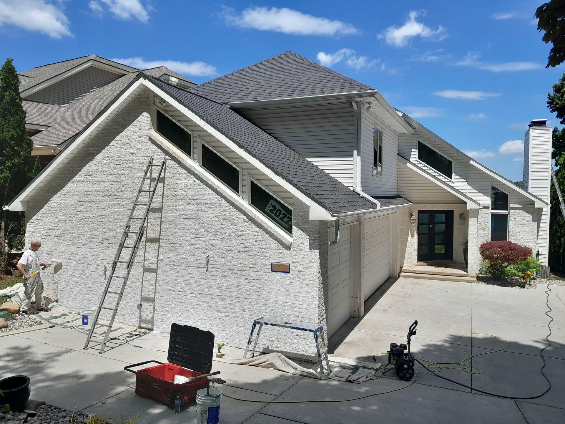 A white brick house with a ladder in front of it