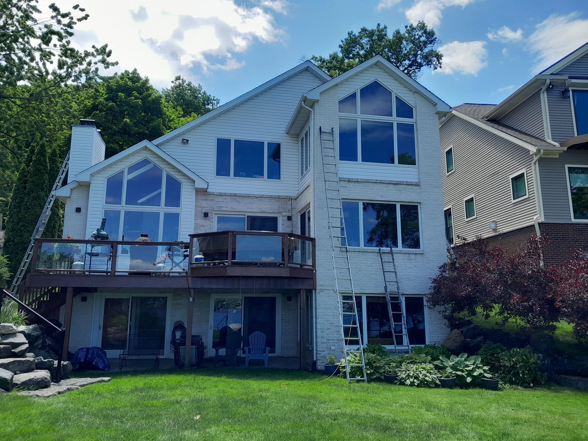A large white house with a lot of windows is sitting on top of a lush green lawn.