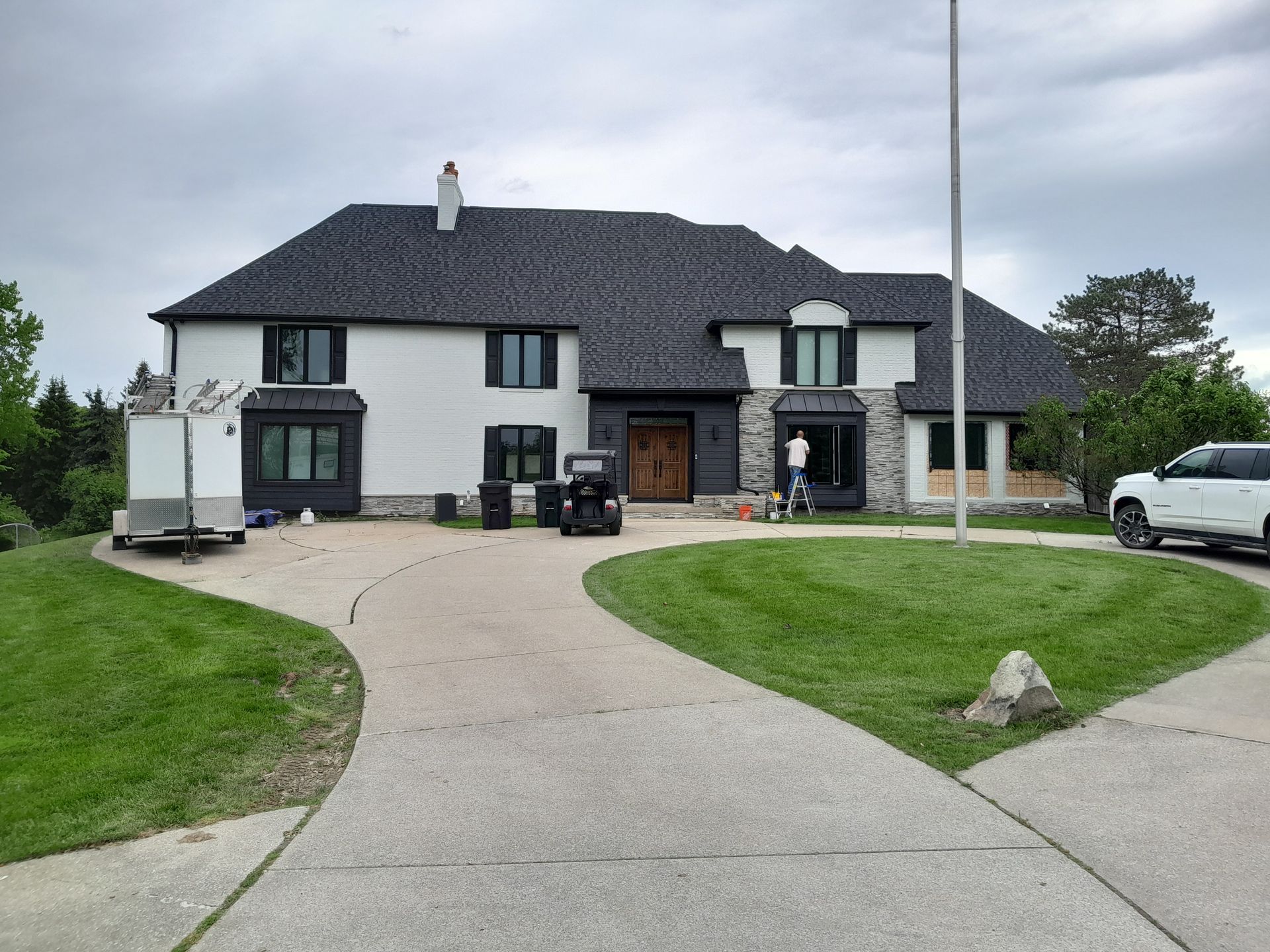 A large white house with a black roof is being painted.