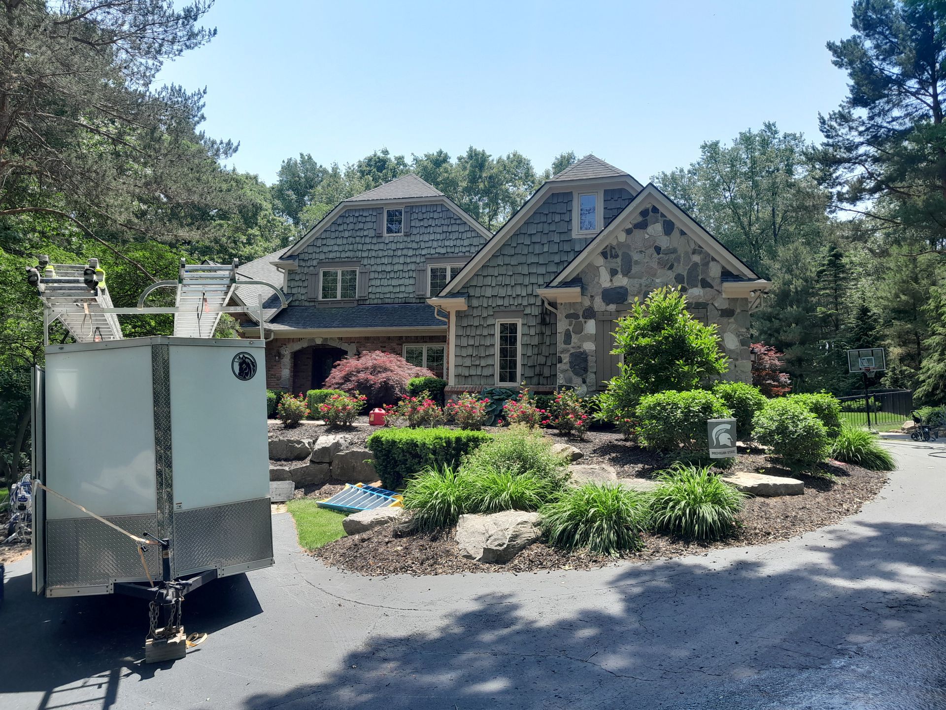 A trailer is parked in front of a large house.