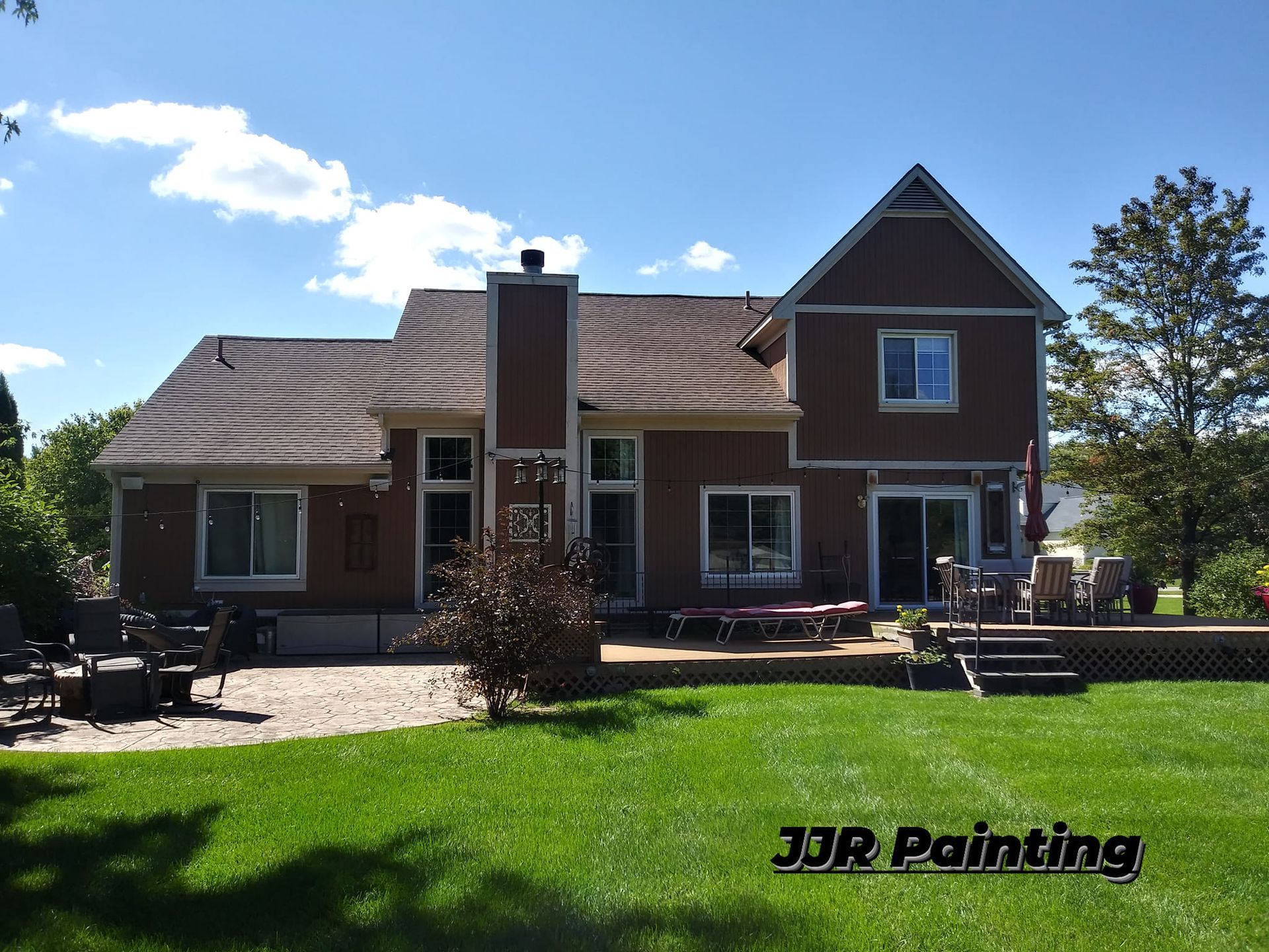 A large brown house with a large lawn in front of it.