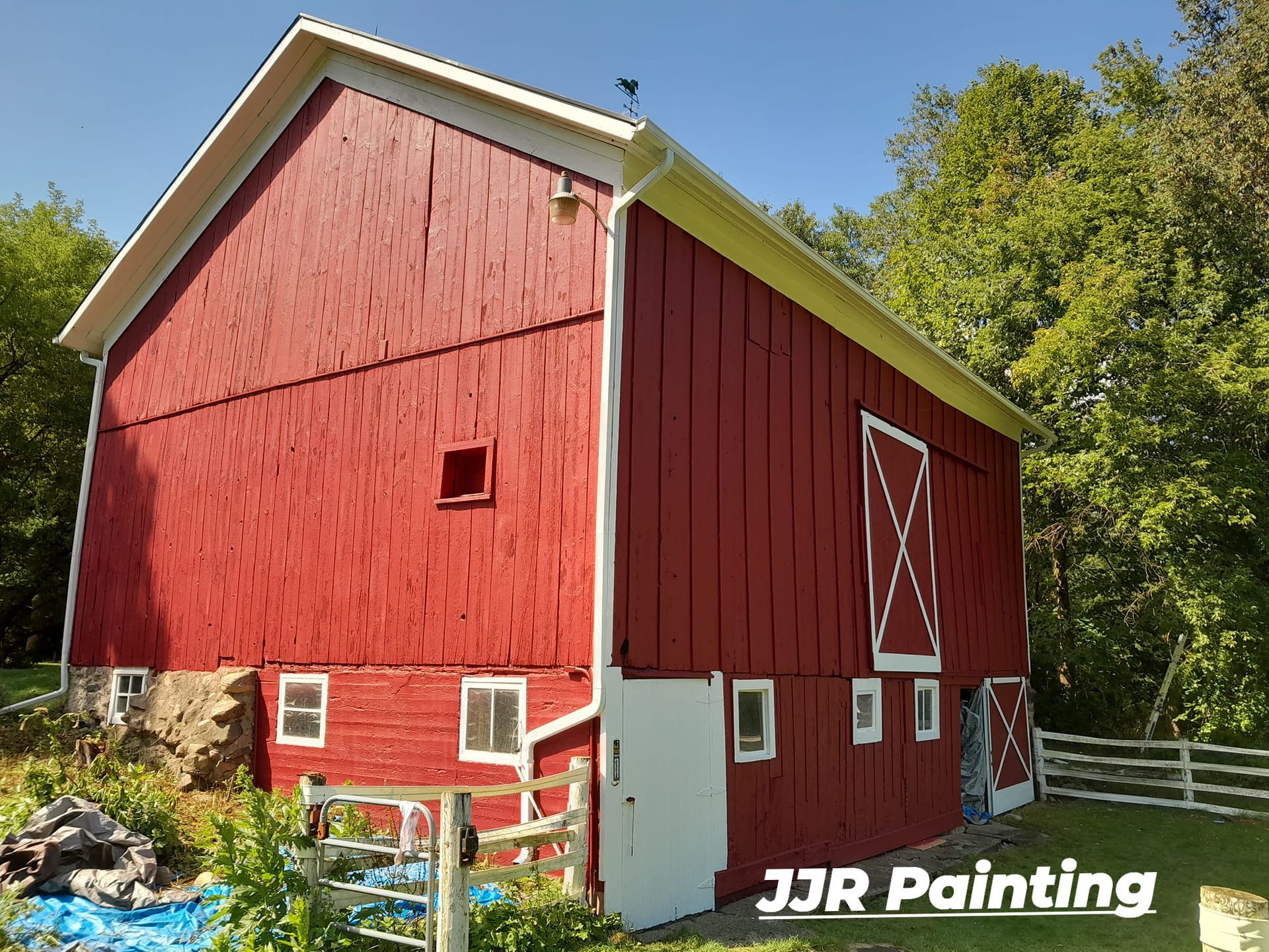 A red barn is being painted by jjr painting