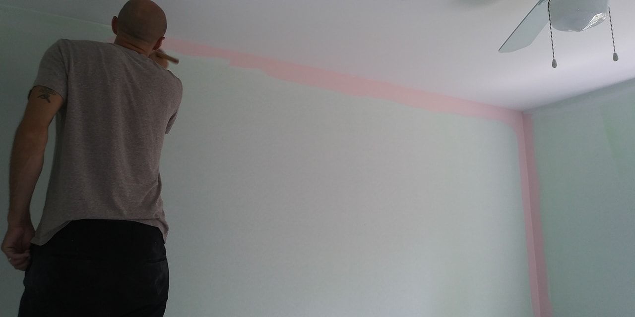 A man is standing in a room with a ceiling fan.