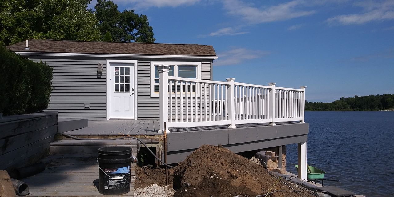 A small house with a deck overlooking a lake