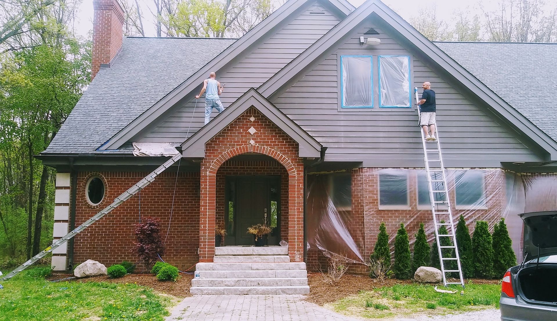 Two men are painting the side of a house.