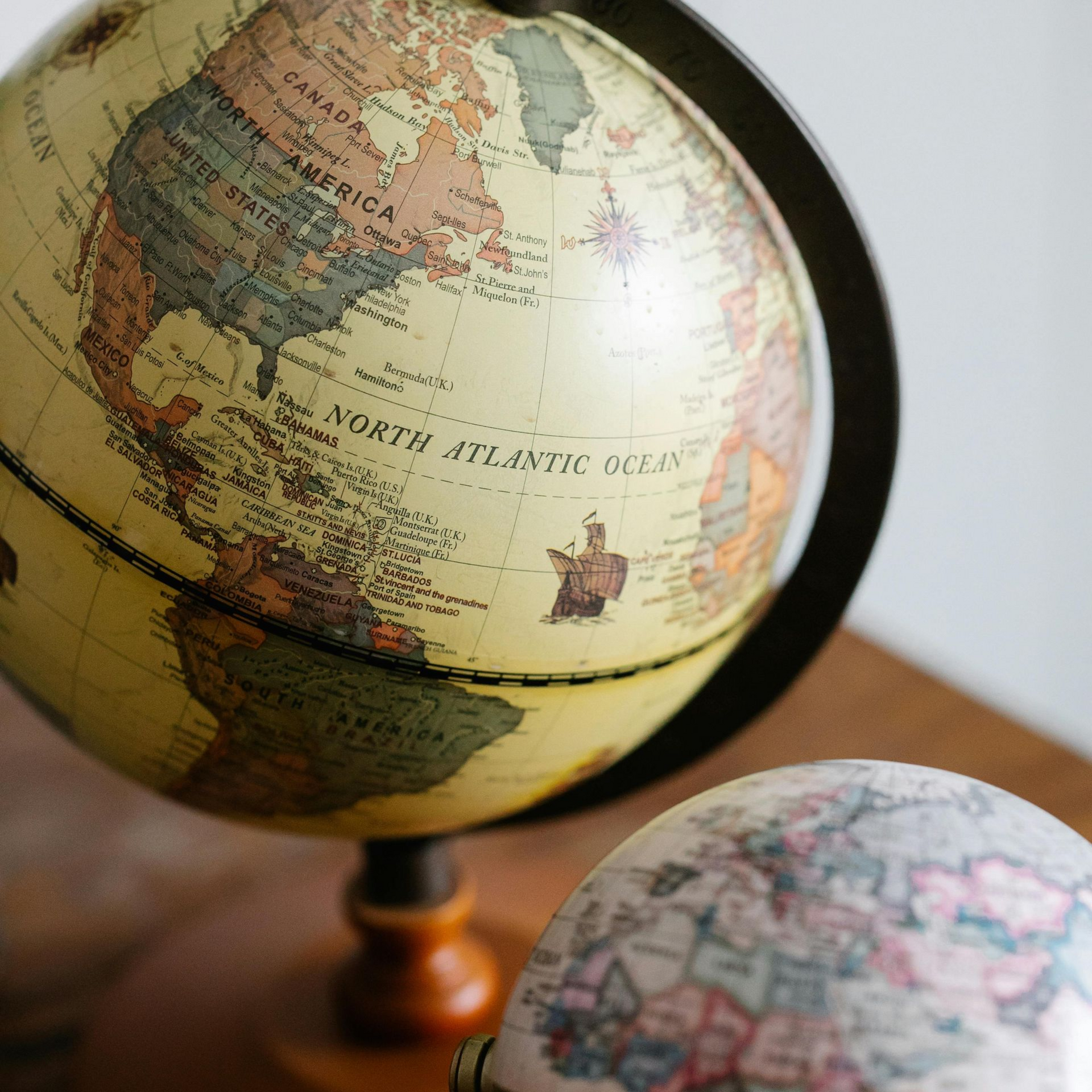 Two antique globes on a wooden table. One shows North America and the North Atlantic Ocean.