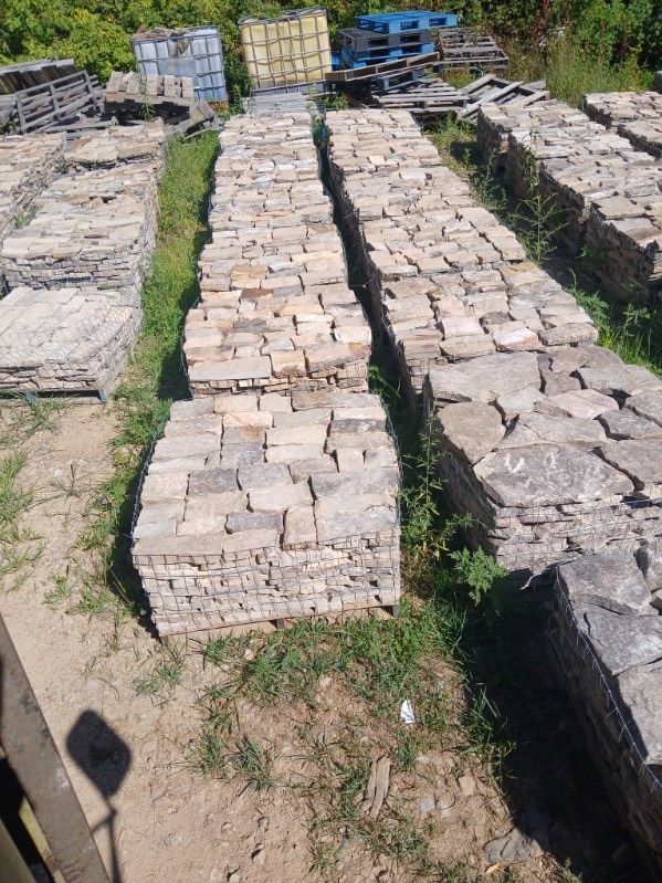 A bunch of bricks are stacked on top of each other in a field.