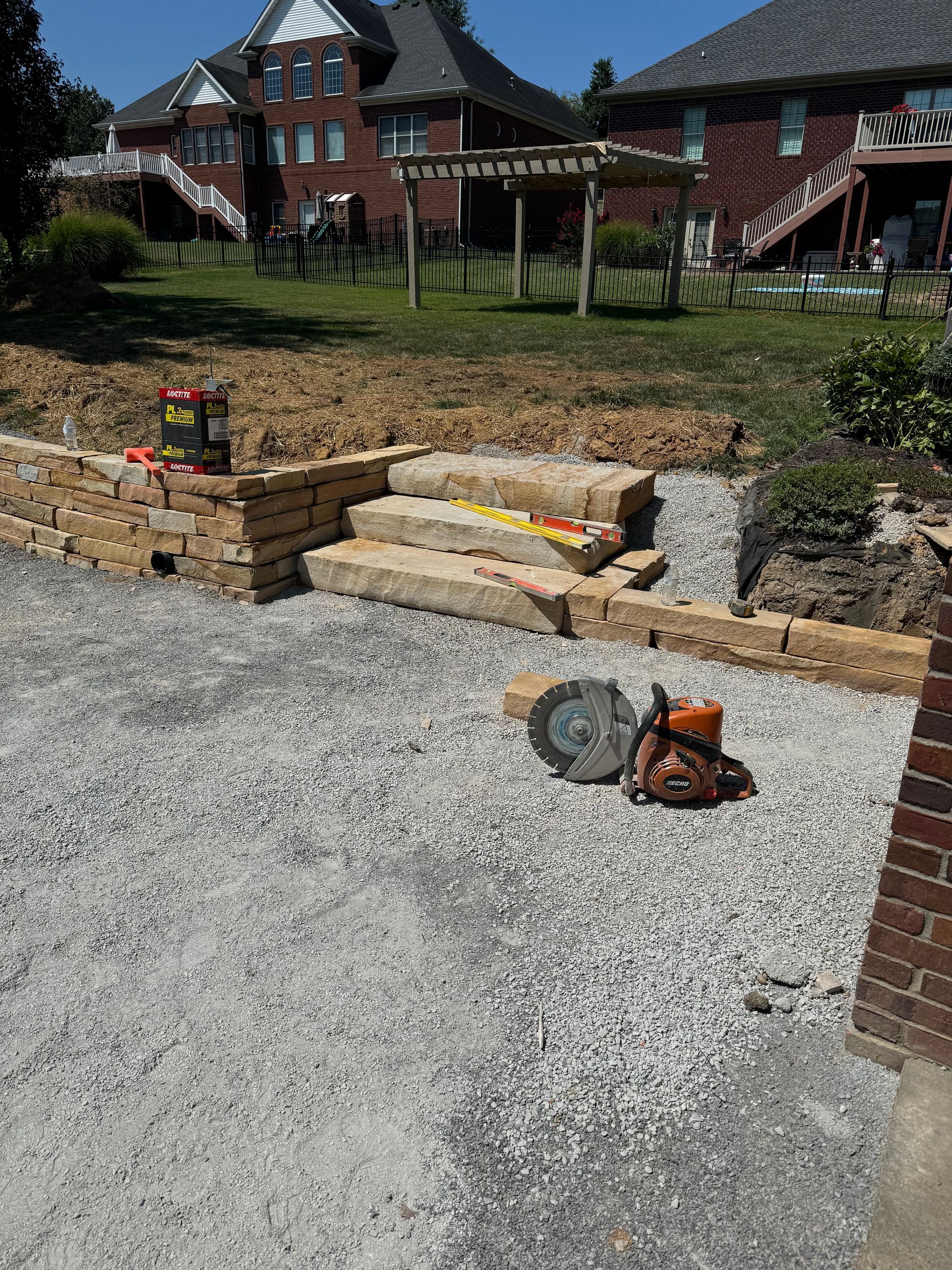 A chainsaw is laying on the ground in front of a brick house.