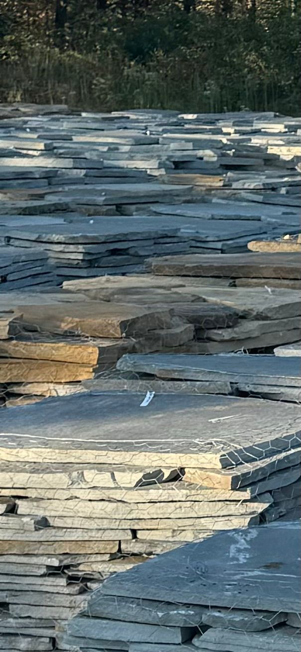A large pile of slate tiles sitting on top of each other in a field.