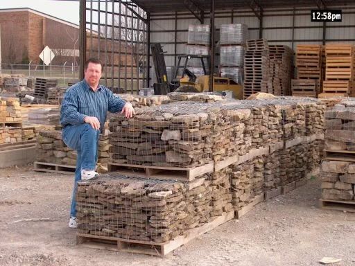 A man is kneeling on a pile of rocks in a warehouse