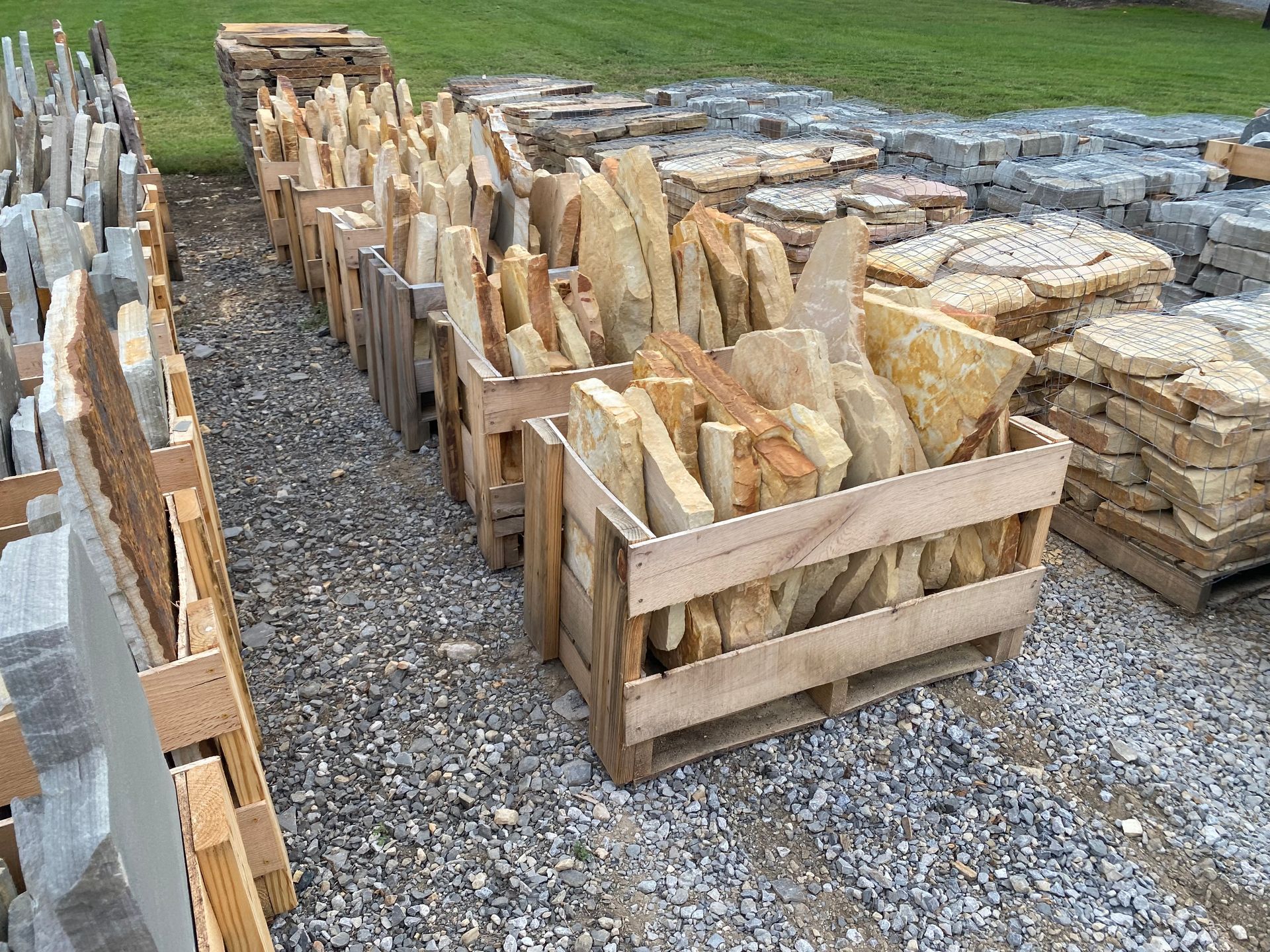 A wooden crate filled with rocks is sitting next to a pile of rocks.