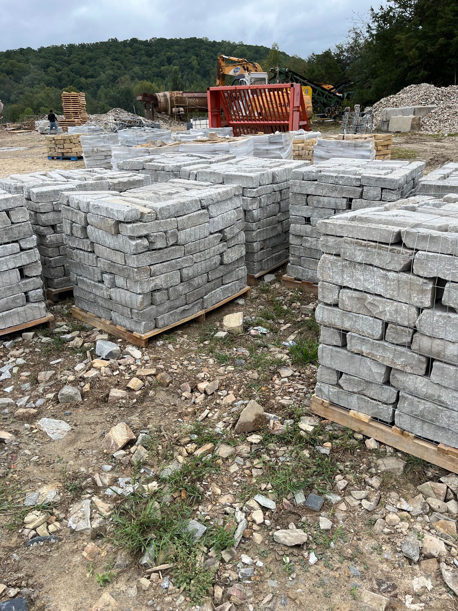 A pile of bricks sitting on top of wooden pallets in a field.