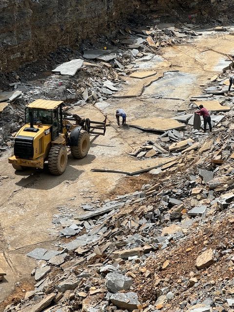 A yellow tractor is driving through a pile of rocks