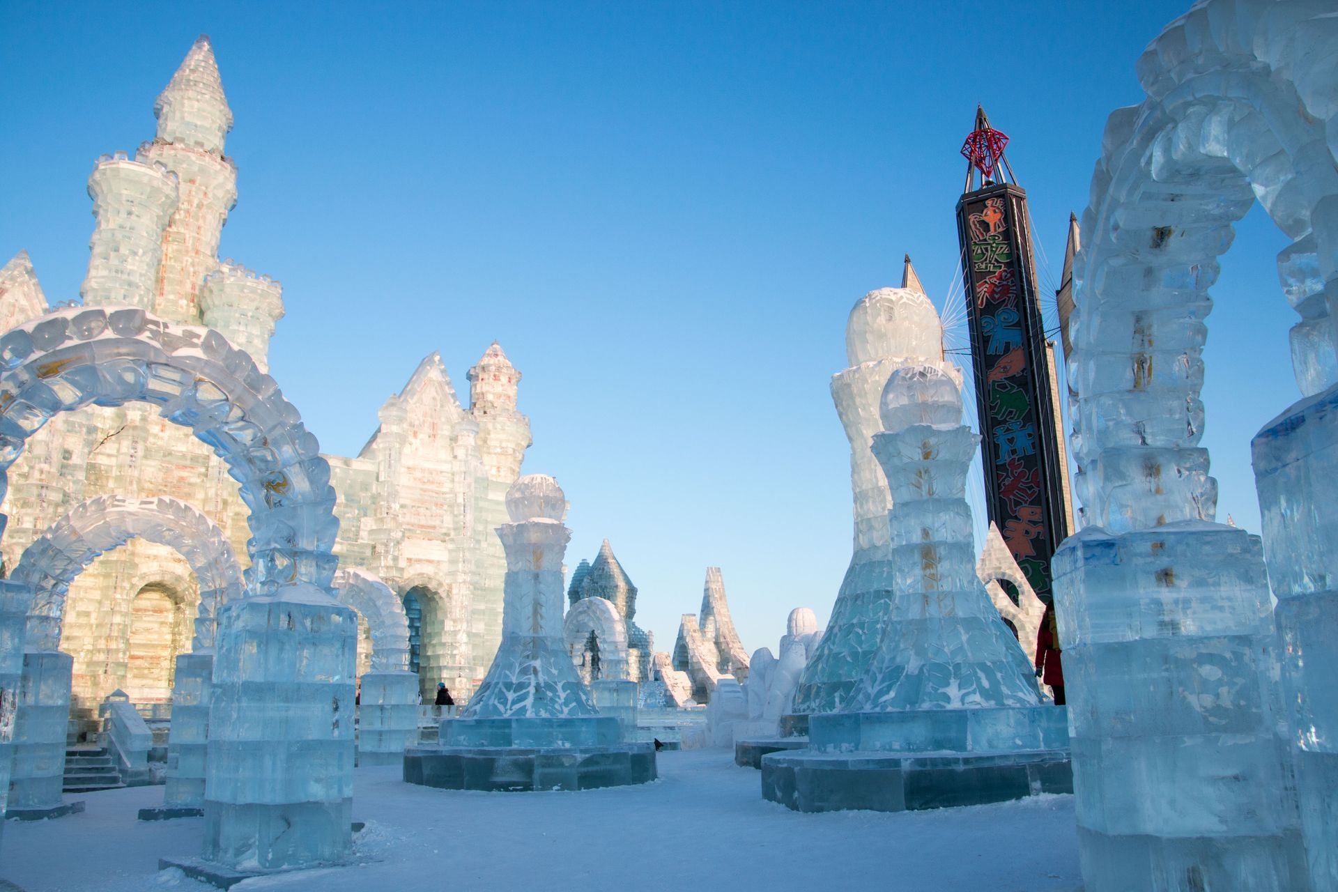 Ice sculptures of arches and chess pieces under a clear blue sky.