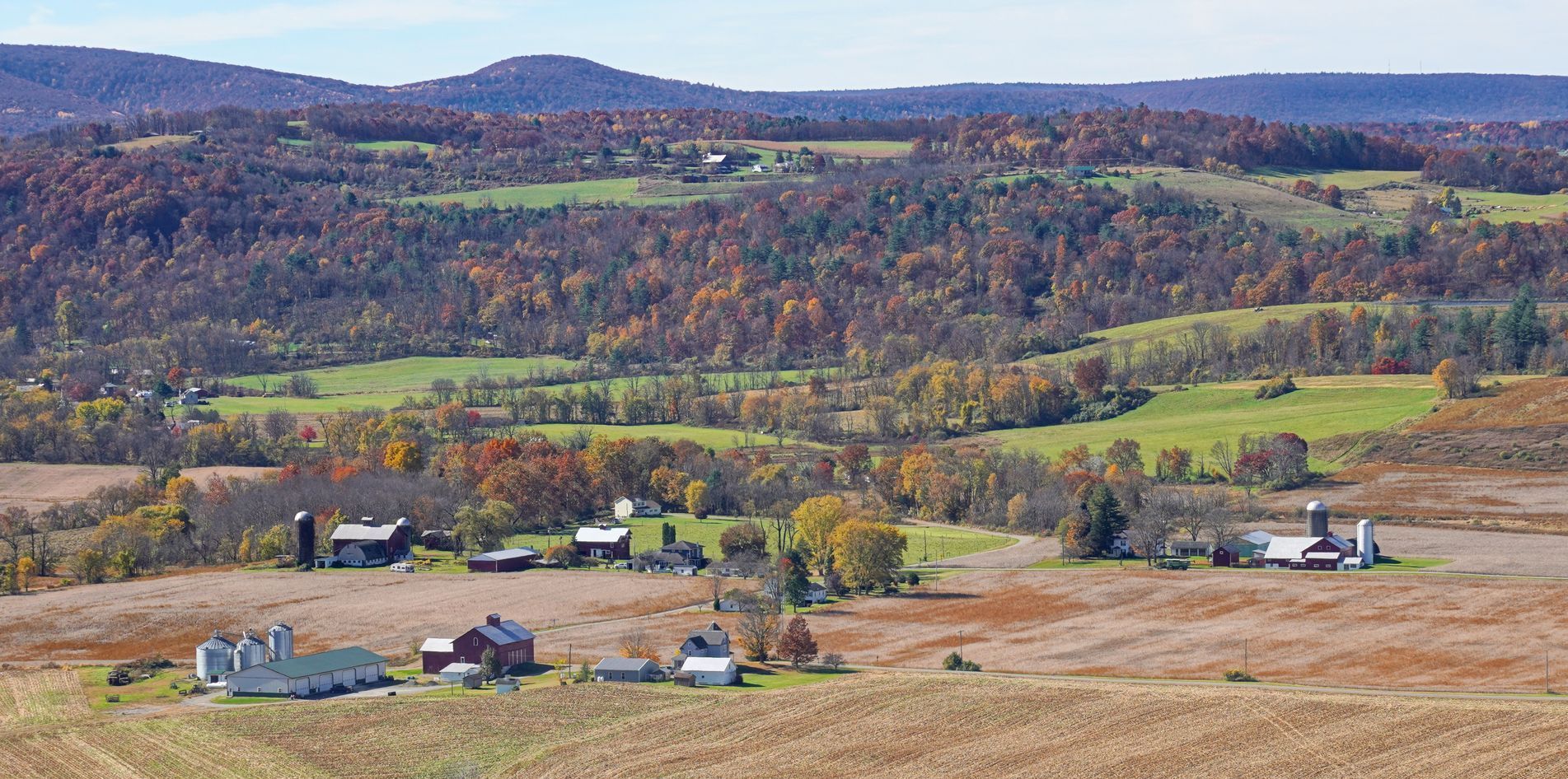 An aerial view of a farm in the middle of a field with mountains in the background.