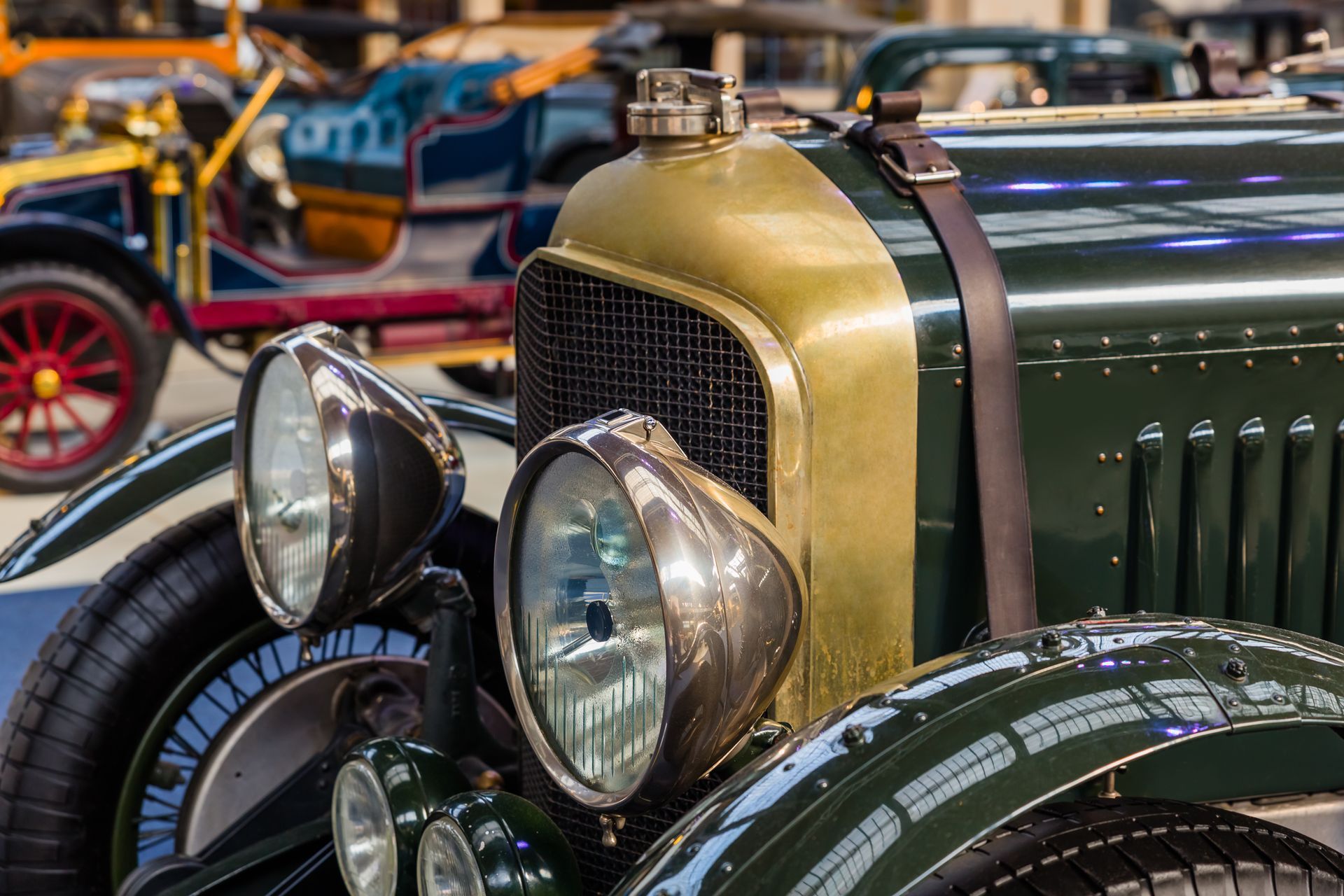 A close up of the front of a green and gold vintage car.