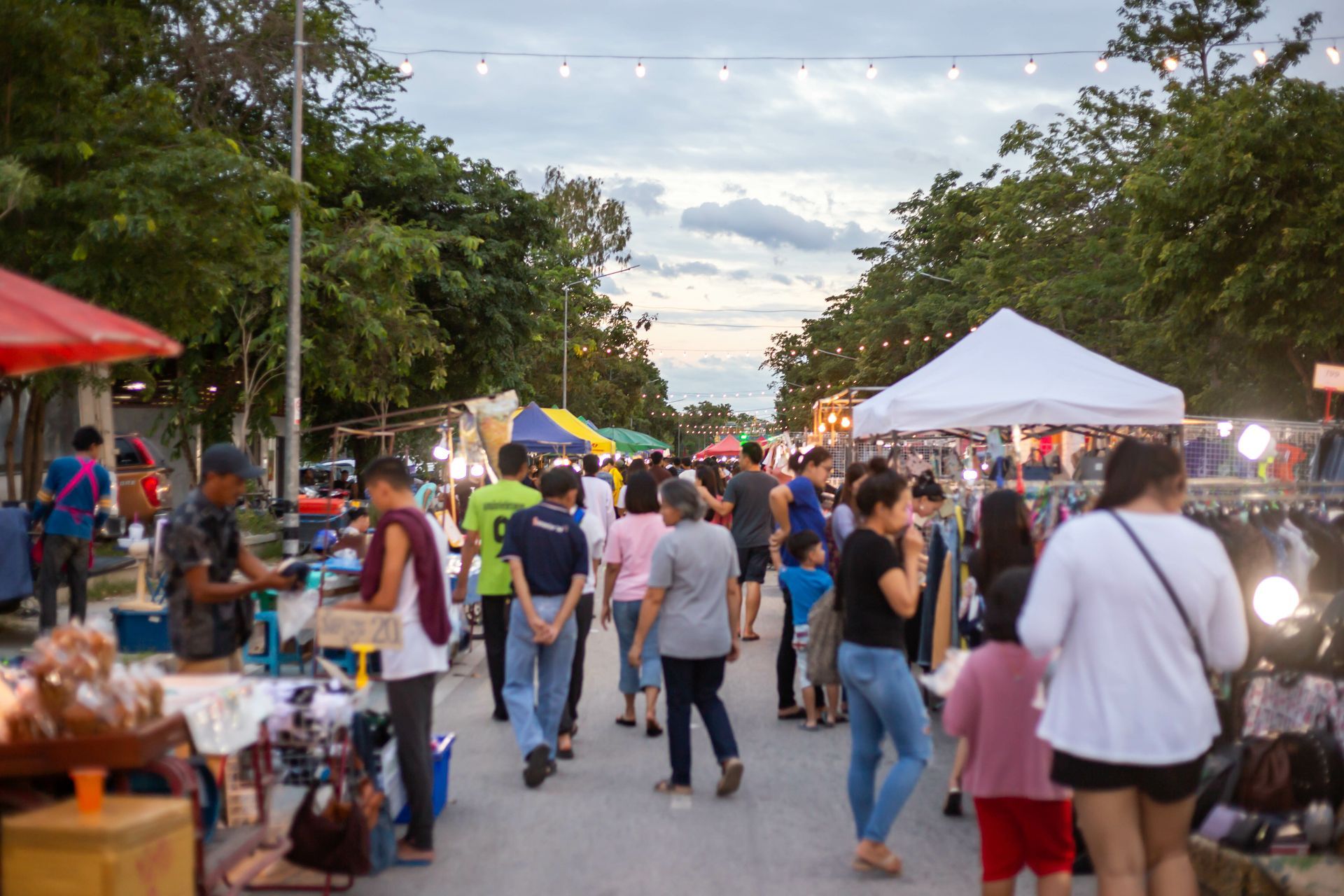 A crowd of people are walking down a street at a market.