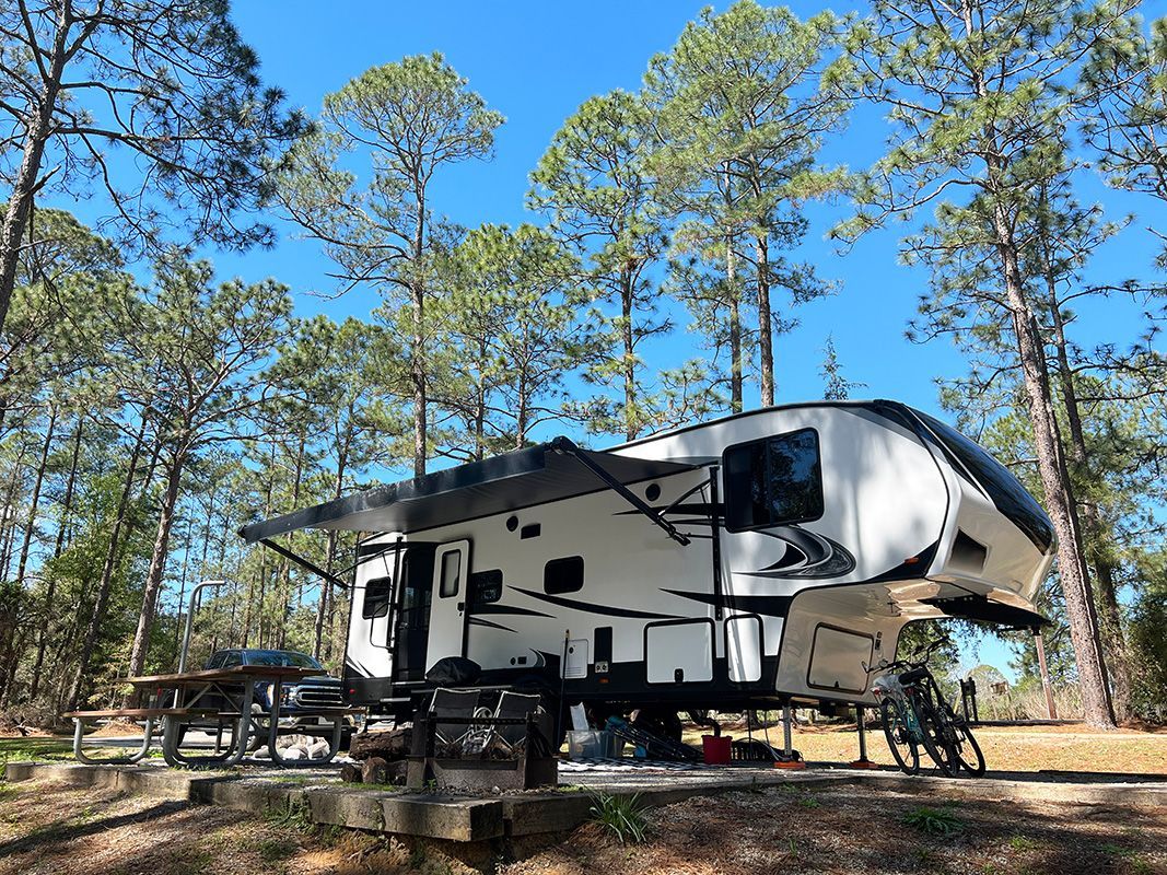 A white rv is parked in the middle of a forest.