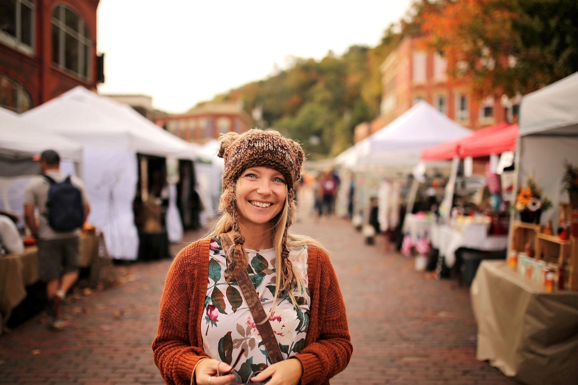 A woman wearing a hat is standing in front of a market.