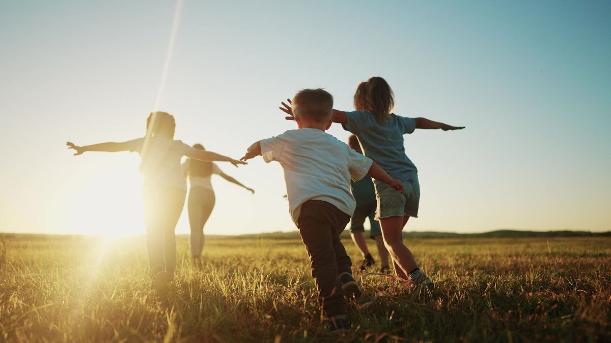 A family is playing in a field at sunset.