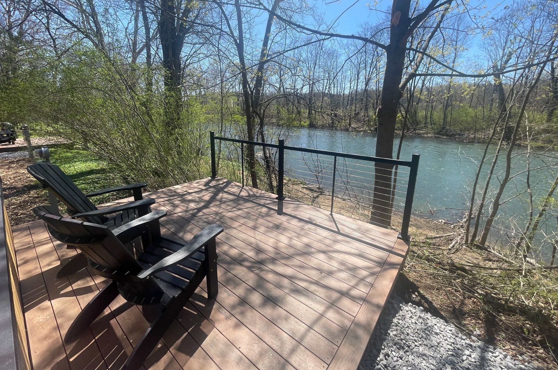 Two chairs are sitting on a wooden deck overlooking a river.