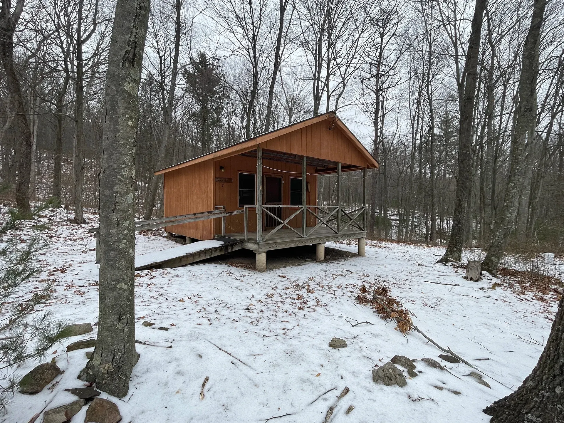Bedroom with a bed, sofa, and round coffee table. A large window offers a view of trees.