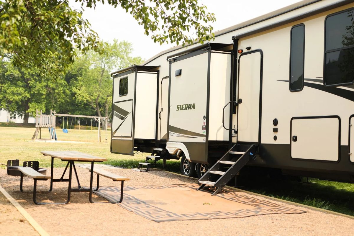 A couple of trailers parked next to each other with a picnic table in front of them.