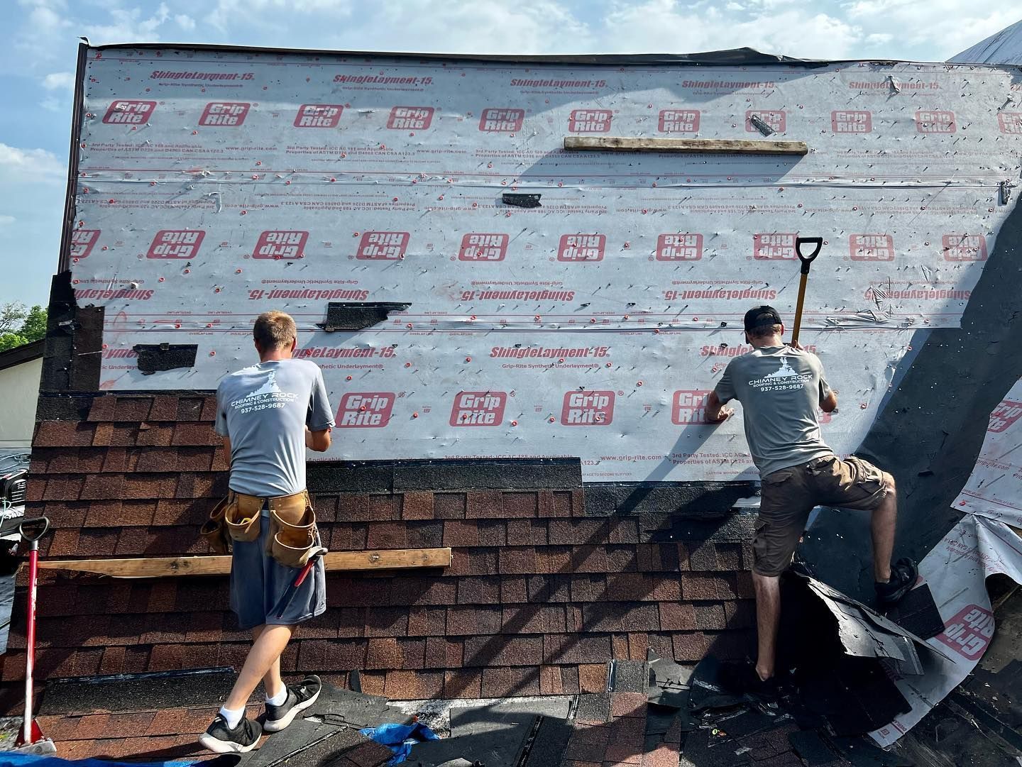 Two men are working on the roof of a building.
