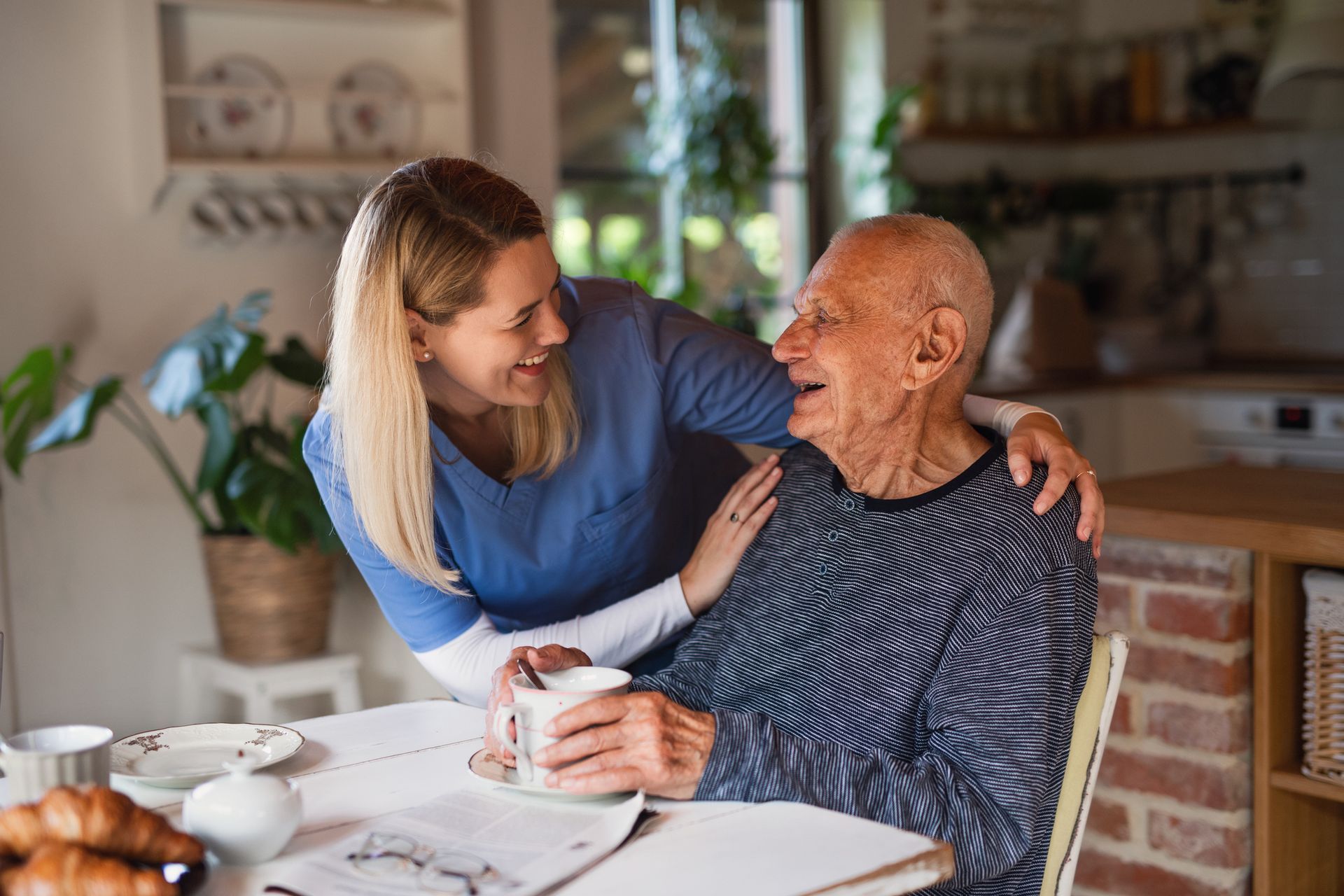 An elderly man is sitting at a table with a nurse.