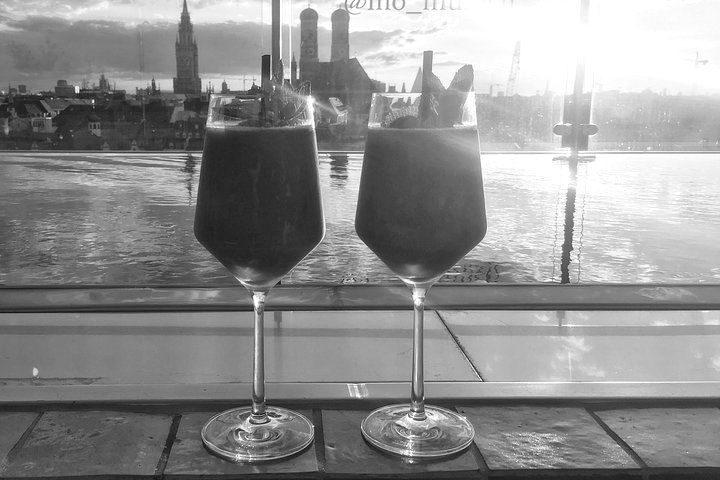 Two wine glasses are sitting on a table in front of a window.