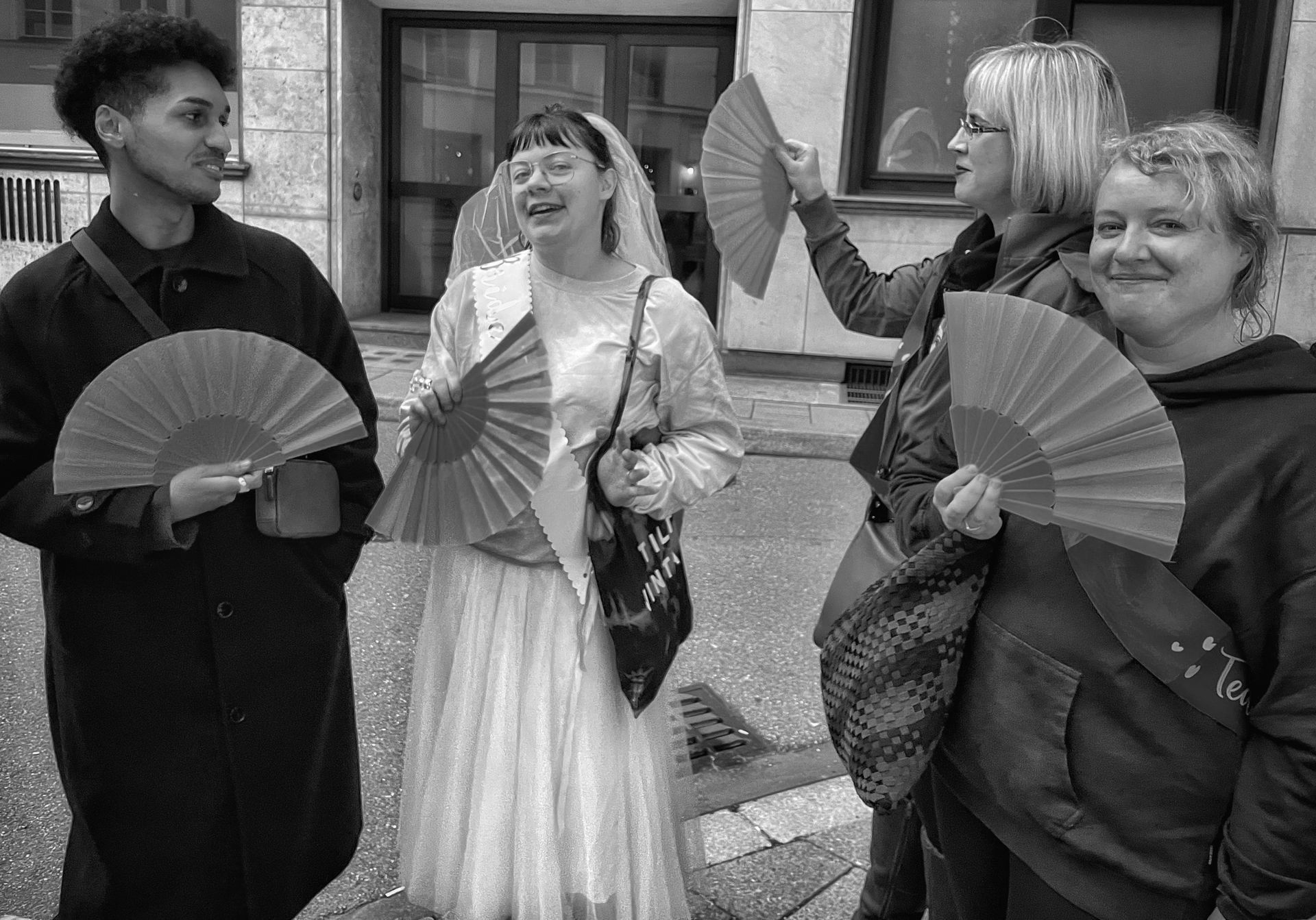 A group of people are standing next to each other holding fans.