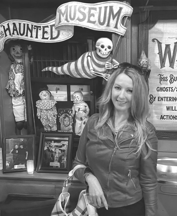 A woman is standing in front of a haunted museum.