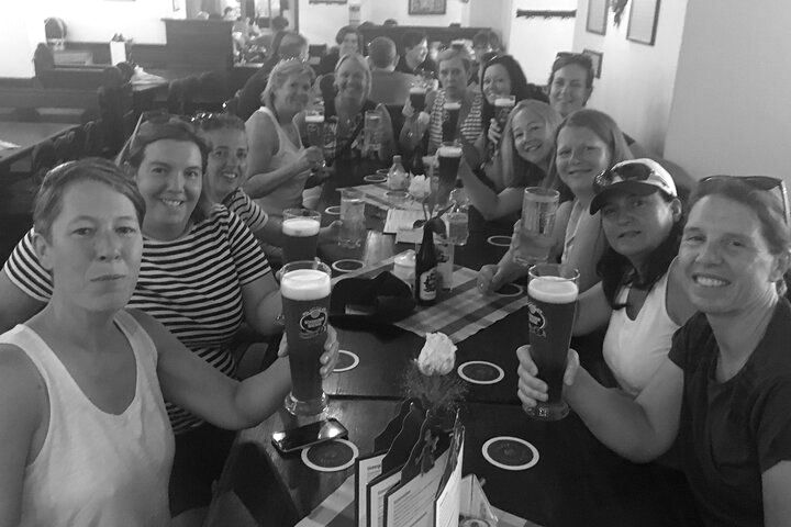A group of women are sitting at a table holding beer glasses.