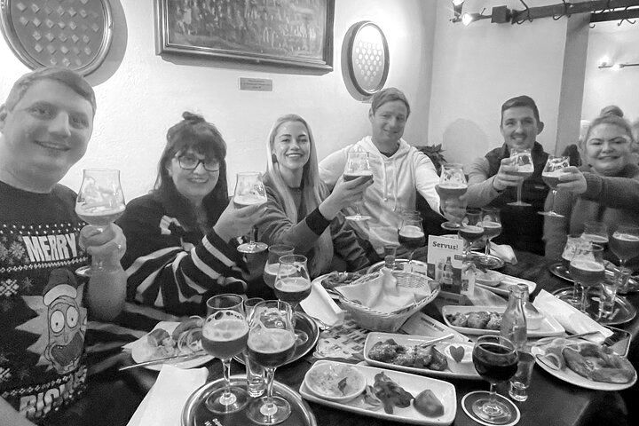 A group of people are sitting at a table holding glasses of beer.
