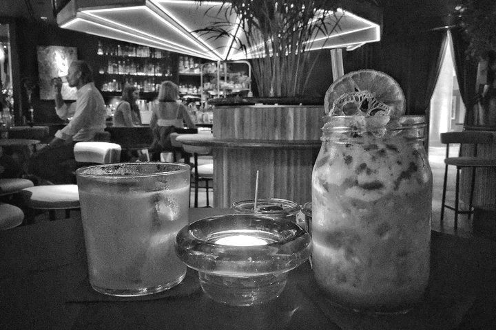 A black and white photo of two drinks on a table in a bar