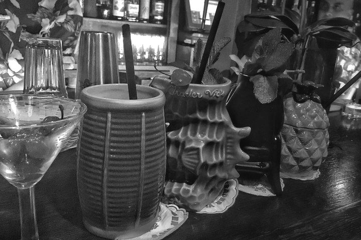 A black and white photo of a bar with drinks and glasses