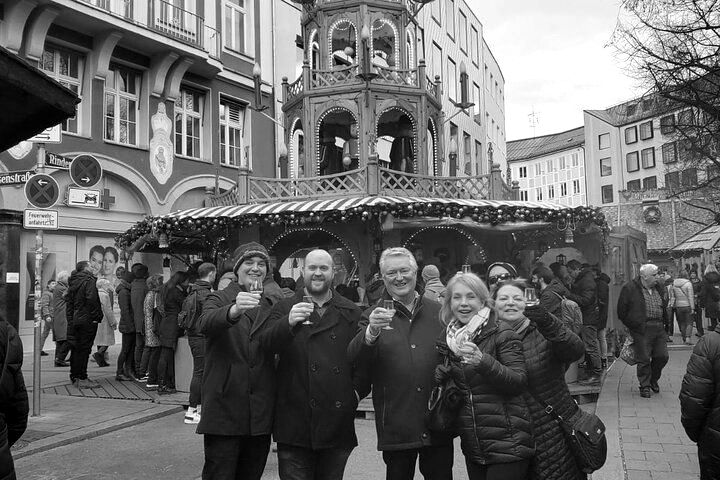 A group of people are standing in front of a christmas market.