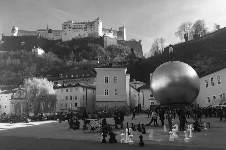 A black and white photo of people playing chess in front of a castle.
