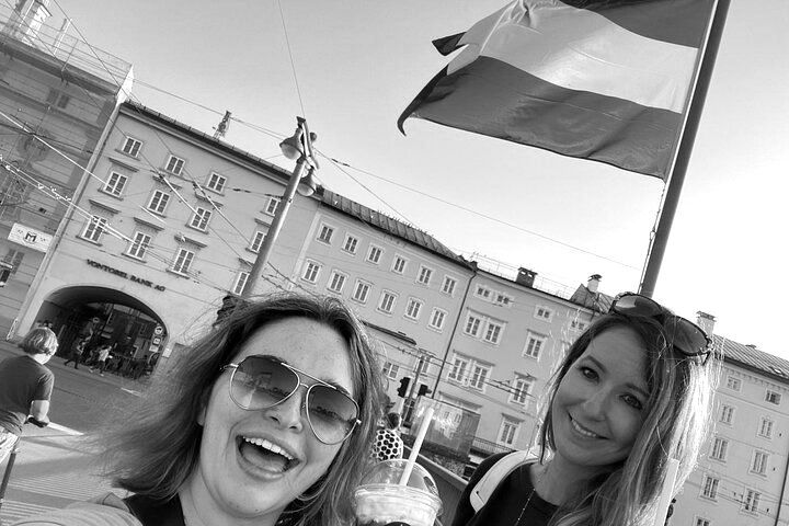 Three women are standing next to each other in front of a flag.
