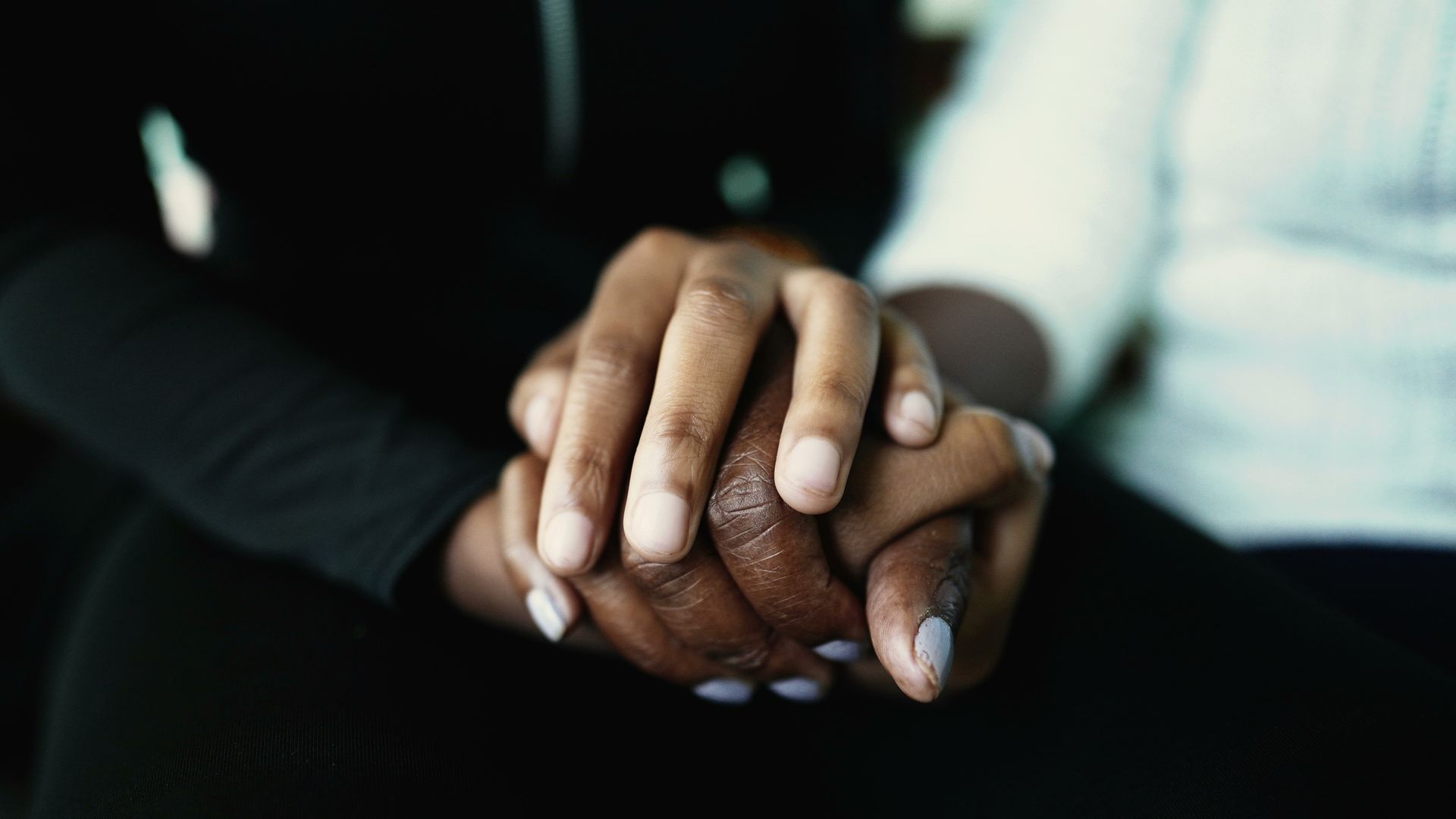 Man's hands clasped over a cane, wearing a plaid shirt and tan pants. Gold wedding ring visible.