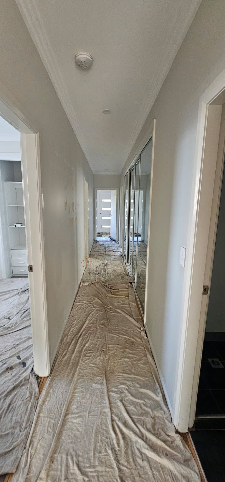 A long hallway with a white sheet on the floor.